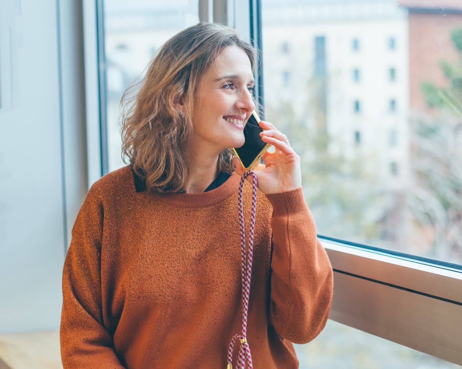 Stéphanie Saint Olive au téléphone, souriante, prête à échanger sur votre projet